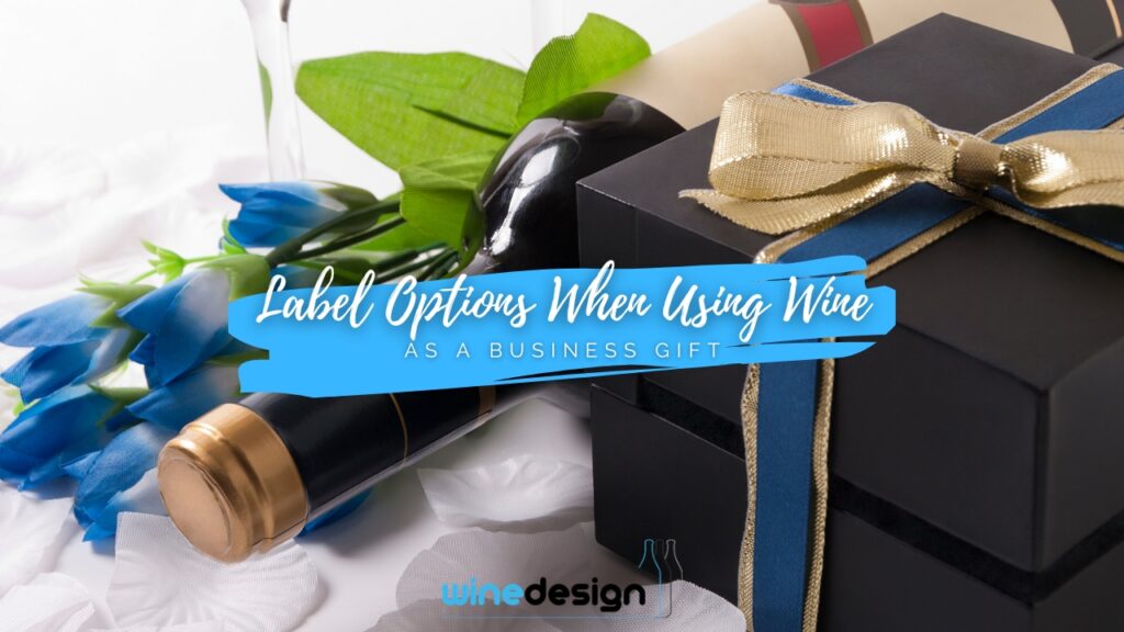 A sophisticated business gift arrangement featuring a wine bottle next to a black gift box tied with a blue and gold ribbon