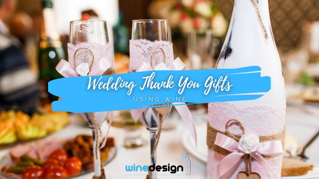 Blog - Wedding A painted wine bottle and matching champagne flutes decorated with pink lace, pink bows, and small white flowers set on a wedding reception table.