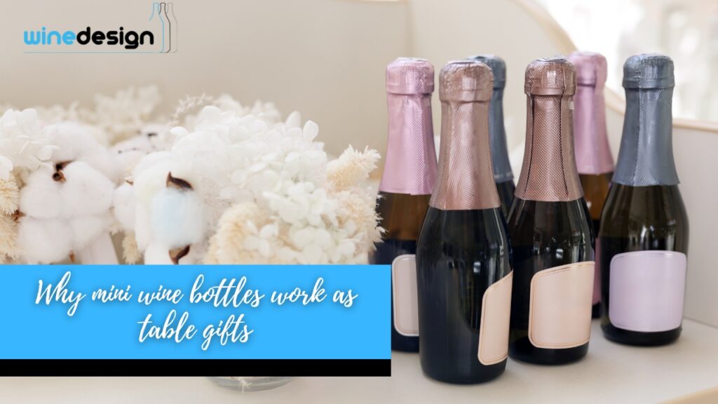 Mini champagne bottles wrapped in metallic foil foil-wrapped necks standing on a table next to white dried flowers.